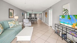 Una sala de estar con sofá, mesa de centro, televisor y estantería.