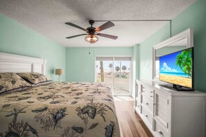 Ein Schlafzimmer mit einem Bett, einem Deckenventilator, einem Fernseher und Blick ins Freie.
