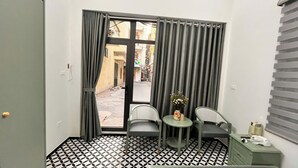 A room with a black and white tiled floor, two chairs, a small table, and a window with curtains.