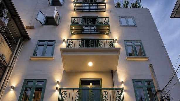 A building with a sign reading 'ERA APARTMENT' above the entrance, featuring a green gate and decorative metal railings.