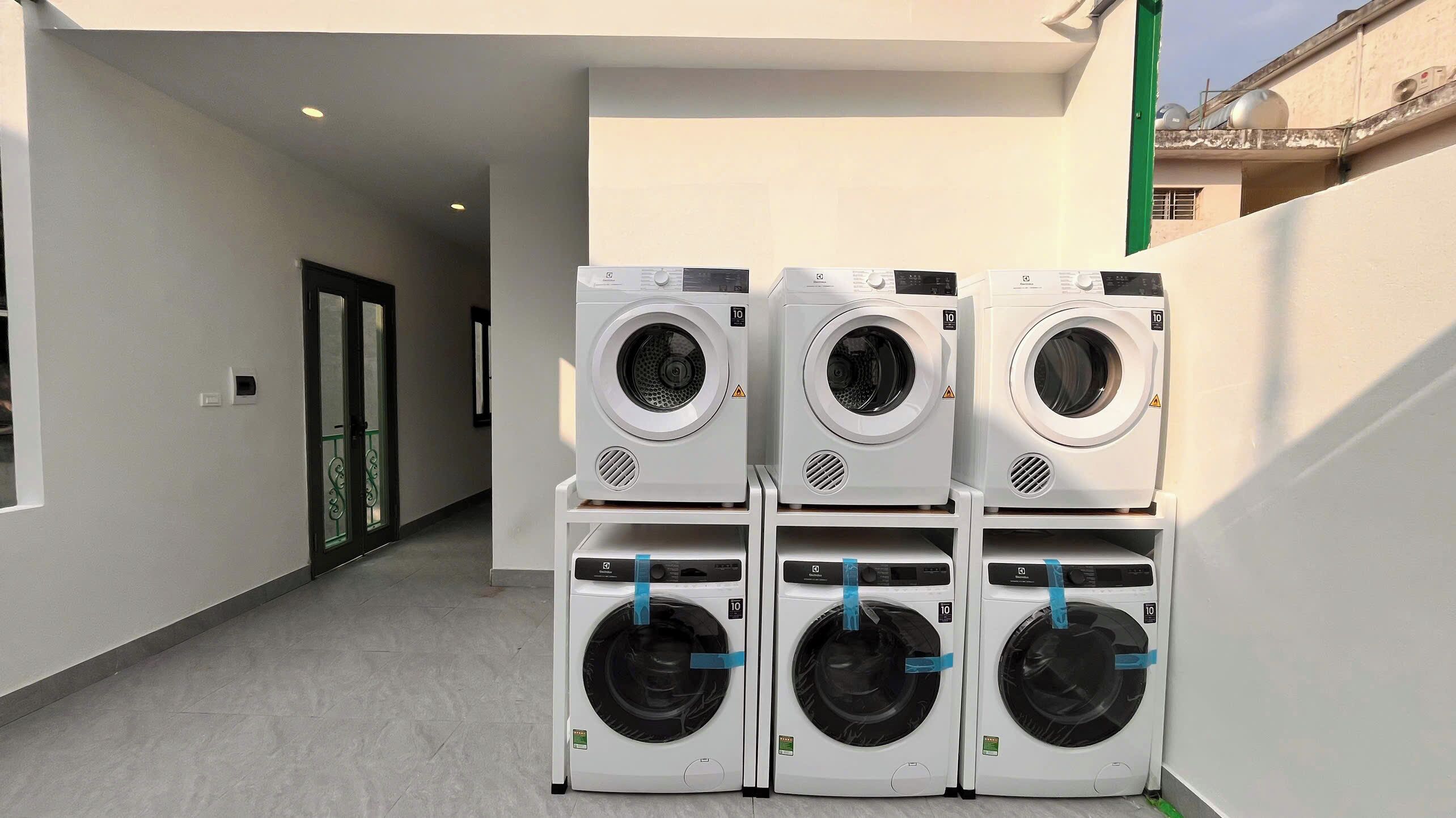 A laundry area with four stacked washing machines, a door, and a hallway.