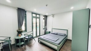 A bedroom with a bed, a chair, a small table, and a window with curtains.