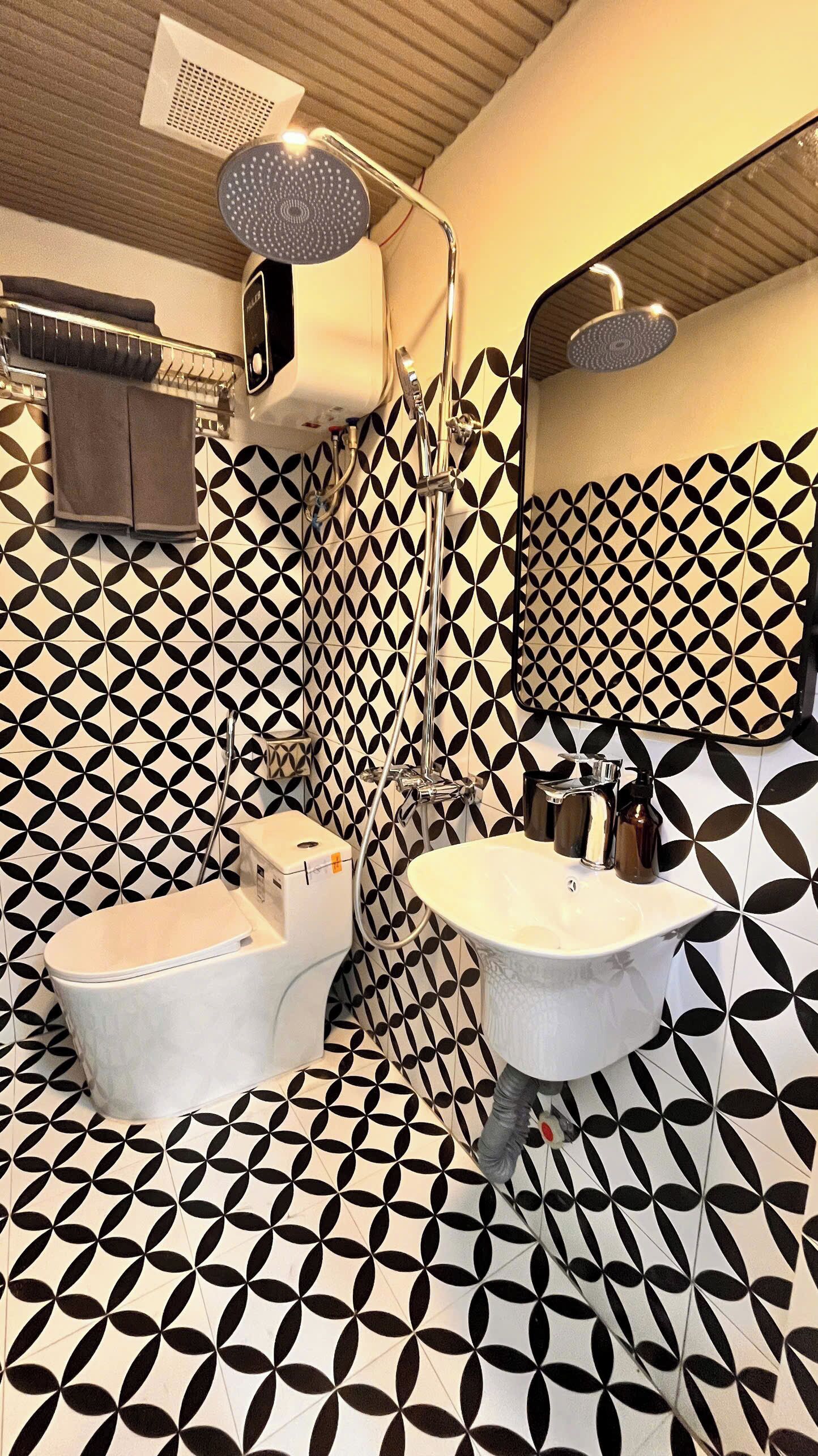A bathroom with a geometric tile pattern, a toilet, a bidet, and a sink.
