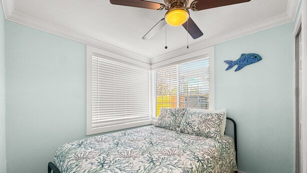 Um quarto com uma cama, um ventilador de teto e uma janela com persianas.