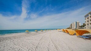 Uma praia com fileiras de guarda-sóis e um edifício com vários andares.