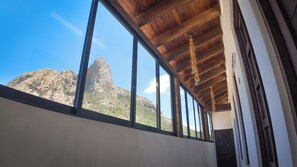A room with large windows, wooden ceiling beams, and a view of a mountain. - Montencino Hotel Boutique  (Ezequiel Montes)
