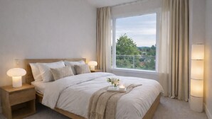 Ein Schlafzimmer mit großem Fenster, einem Bett mit weißer Bettwäsche, zwei Nachttischlampen und einem Nachttisch.