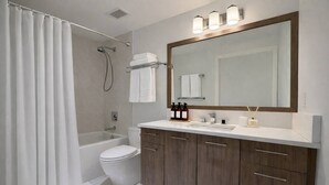 Ein modernes Badezimmer mit Badewanne, Toilette und Waschtisch mit großem Spiegel.