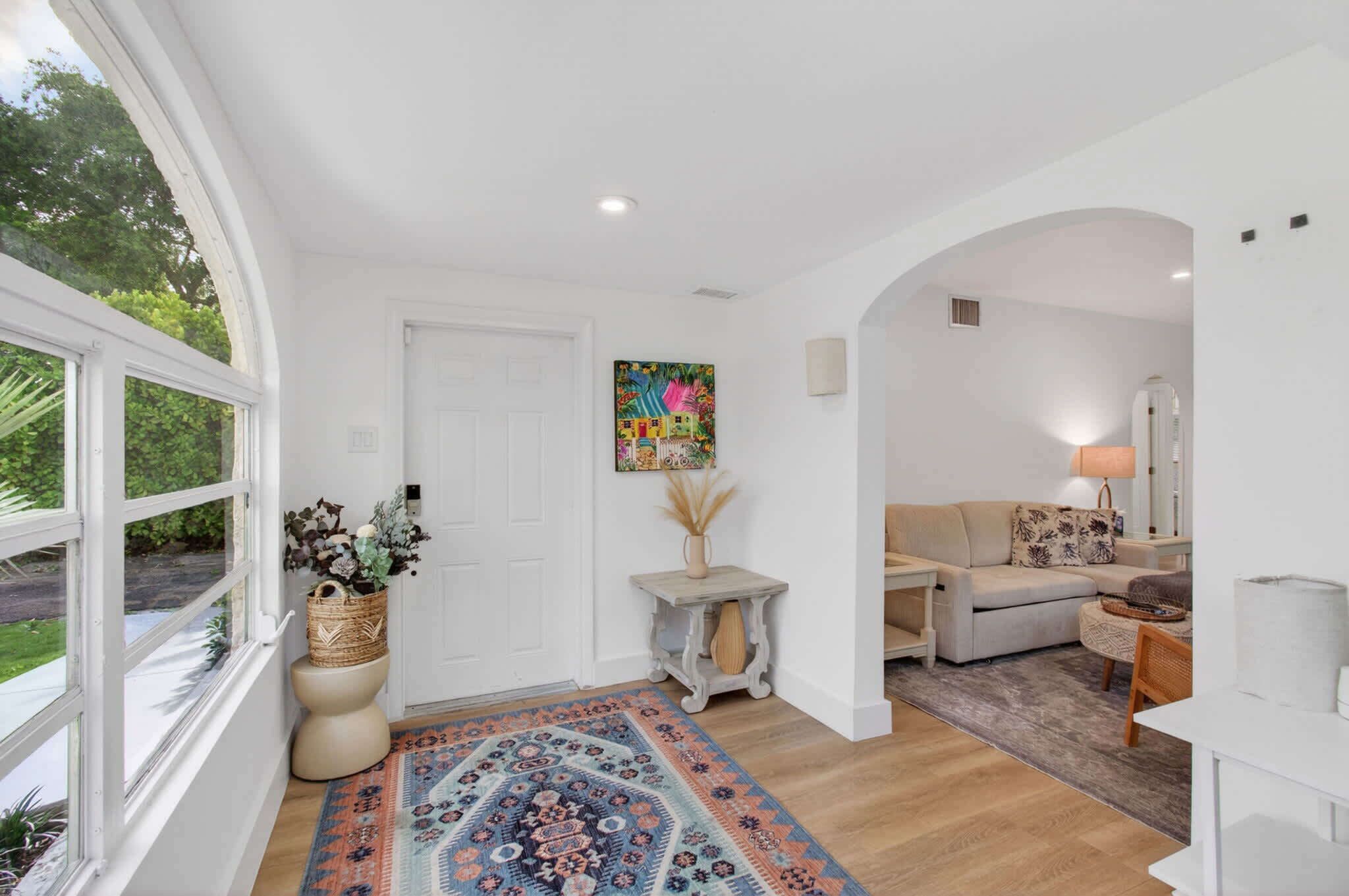 A spacious living area with a large window, a sofa, a coffee table, and a rug.