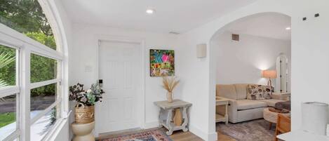 A spacious living area with a large window, a sofa, a coffee table, and a rug.