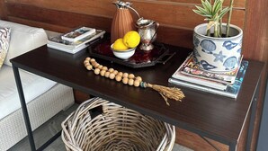 A wooden bench with a table, a woven basket, a potted plant, a tray with lemons, a pitcher, and decorative items. - Room-luxury Couples Suite Ocean View & (Cape Town)