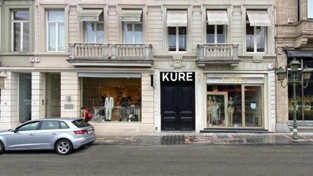 A multi-story building with a prominent 'KURE' sign, large windows, and a balcony. - Fashion Brussels (Brussels)