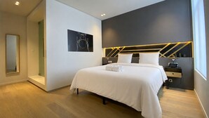 A modern bedroom with a large bed, bedside tables, a mirror, and a wall-mounted light fixture. - Fashion Brussels (Brussels)