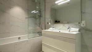 A modern bathroom with a glass-enclosed shower, a white vanity with a mirror, and a toilet. - Fashion Brussels (Brussels)