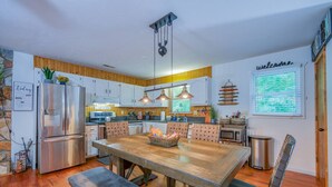 Uma cozinha moderna com uma mesa de jantar de madeira, eletrodomésticos embutidos e uma placa com a palavra 'Welcome'.