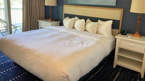 A hotel room with a large bed, two bedside tables, a chair, a window with curtains, and artwork on the wall.
