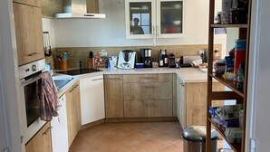 A kitchen with wooden cabinets, a built-in oven, a sink, and a stainless steel trash bin. - Belle-Île-en-Mer — Large family home 12 pers · Garden · 5 min from Donner (Bangor)