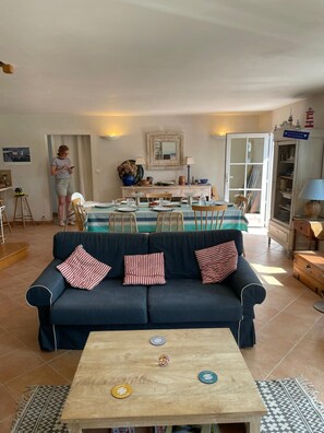 Ein Wohnzimmer mit einer Couch, einem Holztisch und einem Essbereich mit Tisch für zwei Personen.