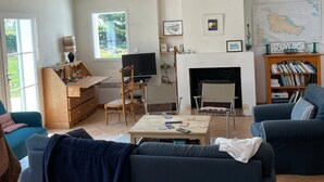 A living room with a sofa, television, fireplace, bookshelf, and a map on the wall. - Belle-Île-en-Mer — Large family home 12 pers · Garden · 5 min from Donner (Bangor)