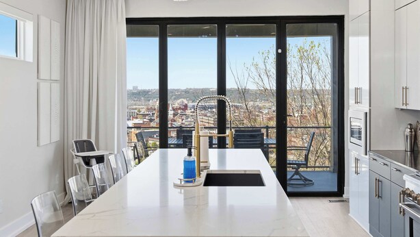 Eine moderne Küche mit einer großen Kochinsel, Blick auf die Stadt und einem Essbereich mit Stühlen.