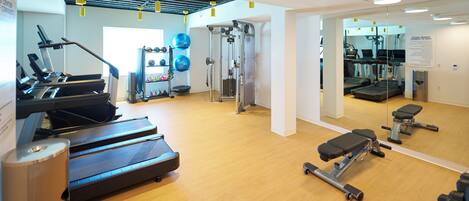 A gym with treadmills, weight machines, and exercise balls.