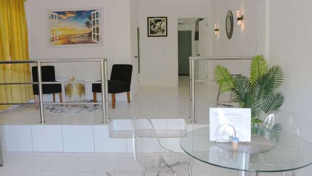 A hotel lobby with a glass table, chairs, a yellow curtain, and artwork on the walls. - Cozy 1-bedroom apartment in beautiful Laborie with AC (Laborie)