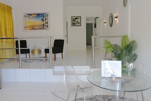 A hotel lobby with a glass table, chairs, a yellow curtain, and artwork on the walls. - Cozy 1-bedroom apartment in beautiful Laborie with AC (Laborie)