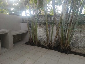 A tiled patio area with a concrete bench, bamboo plants, and a chain-link fence. - Spacious, centrally located residence with a private pool! Perfect for Families! (Cancún)