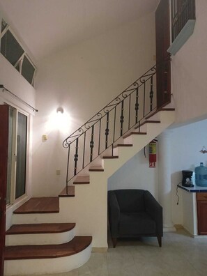 A staircase with a handrail, a black sofa, a water dispenser, and a fire extinguisher. - Family home in a safe neighborhood with spacious bedrooms and a private pool (Cancún)