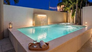 A rectangular pool with a waterfall feature, surrounded by palm trees and a night sky. - Spacious, centrally located residence with a private pool! Perfect for Families! (Cancún)