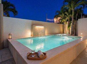 A rectangular pool with a waterfall feature, surrounded by palm trees and a night sky. - Spacious, centrally located residence with a private pool! Perfect for Families! (Cancún)