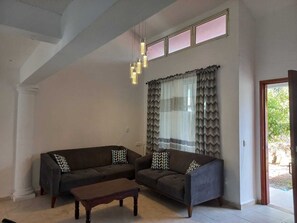 A living room with two sofas, a coffee table, and a large window with curtains. - Family home in a safe neighborhood with spacious bedrooms and a private pool (Cancún)