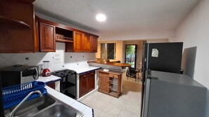 A compact kitchen with wooden cabinets, a gas stove, a sink, and a refrigerator. - Spacious, centrally located residence with a private pool! Perfect for Families! (Cancún)