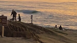 Eine Strandansicht mit Sonnenuntergang, Wellen und Menschen nahe der Küste.