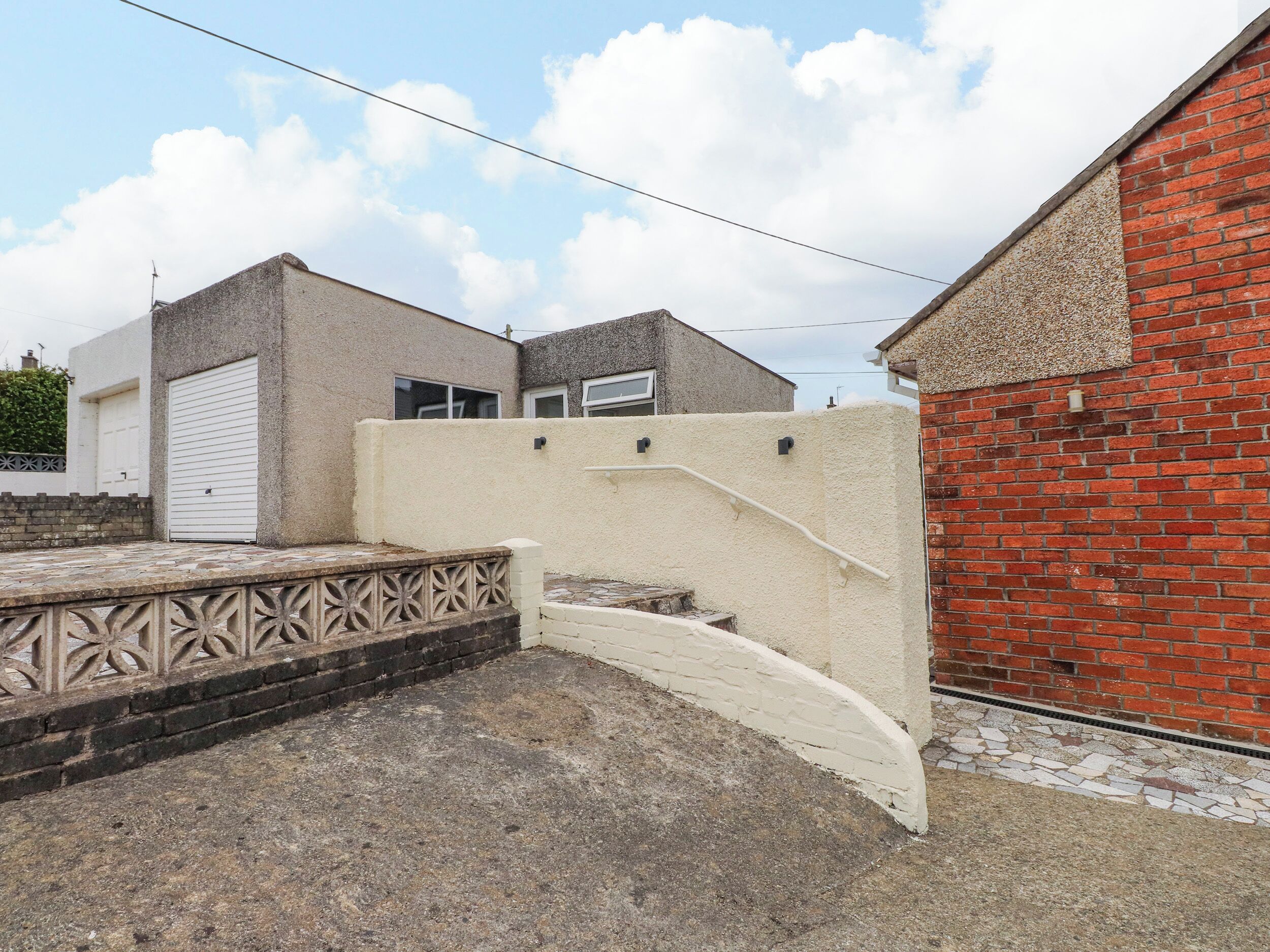 A gated area with a concrete staircase leading to a building with a white garage door.