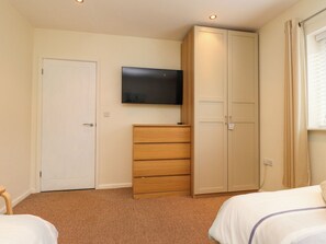 Ein Schlafzimmer mit einem Bett, einem Kleiderschrank, einem Fernseher und einer Tür.