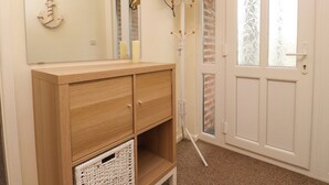 A room with a wooden cabinet, a mirror, a door with frosted glass panels, and a light fixture. - Gelli - Morfa Nefyn (Pwllheli)