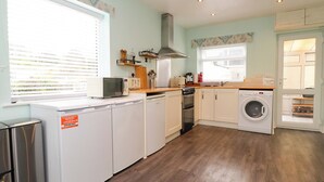 A compact kitchen with a dishwasher, oven, microwave, and a washing machine. - Gelli - Morfa Nefyn (Pwllheli)