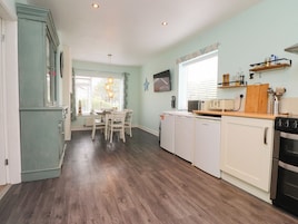 A kitchen with a dining table, white cabinets, a refrigerator, a microwave, and a stove.