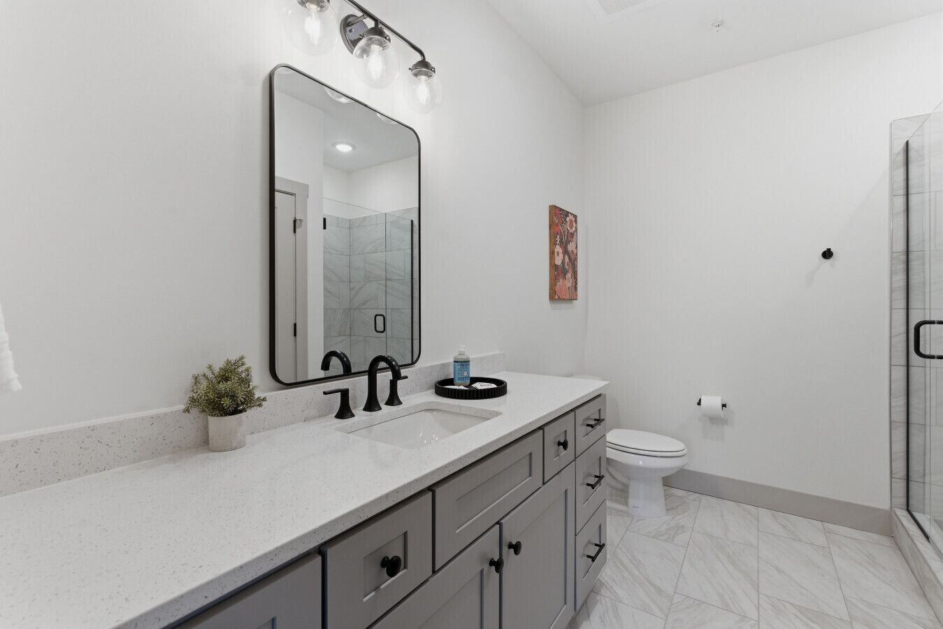 Une salle de bain moderne avec un grand miroir, une douche et des toilettes.