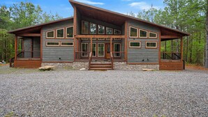 A two-story log cabin with a front porch, large windows, and a stone foundation. - The Retreat at Red Fern - Excellent Location (Broken Bow)