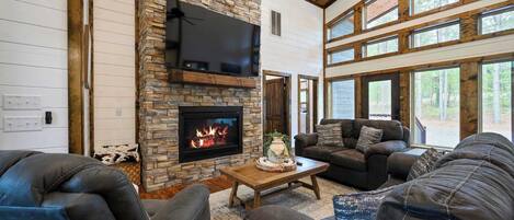 Una sala de estar acogedora con chimenea de piedra, sofás de cuero y ventanas amplias.
