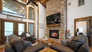 A cozy living room with leather sofas, a fireplace, and a stone accent wall. - The Retreat at Red Fern - Excellent Location (Broken Bow)