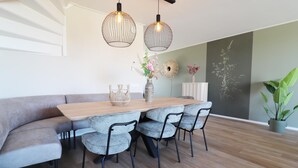 A dining area with a wooden table, grey upholstered bench, and four grey chairs. - New, Luxury Holiday Home in the Heart of Friesland (Leons)