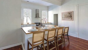 Una cucina con isola centrale, mobili bianchi e zona pranzo con quattro sedie.