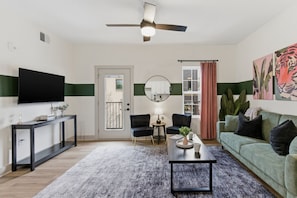 Un salon moderne doté d’un téléviseur à écran plat, d’un ventilateur de plafond, d’un canapé, d’une table basse et d’un coin repas avec une table et des chaises.