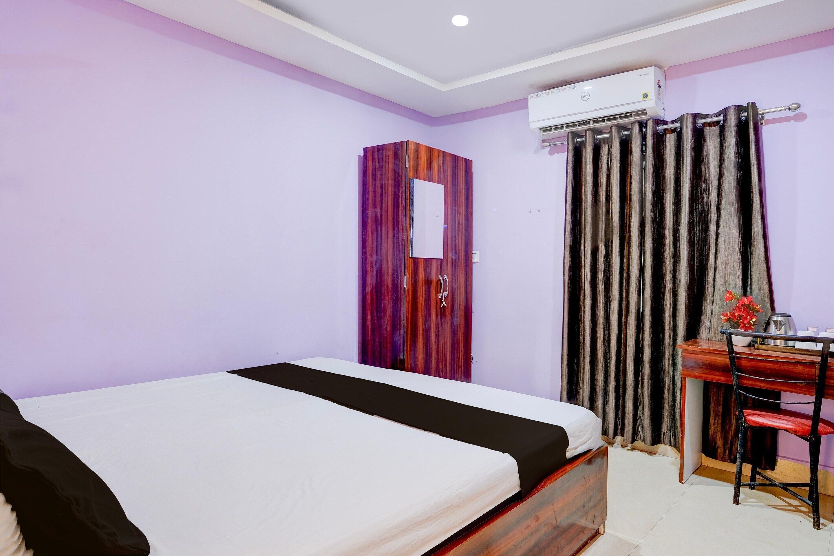 Un dormitorio con cama, escritorio, silla, aire acondicionado y armario.