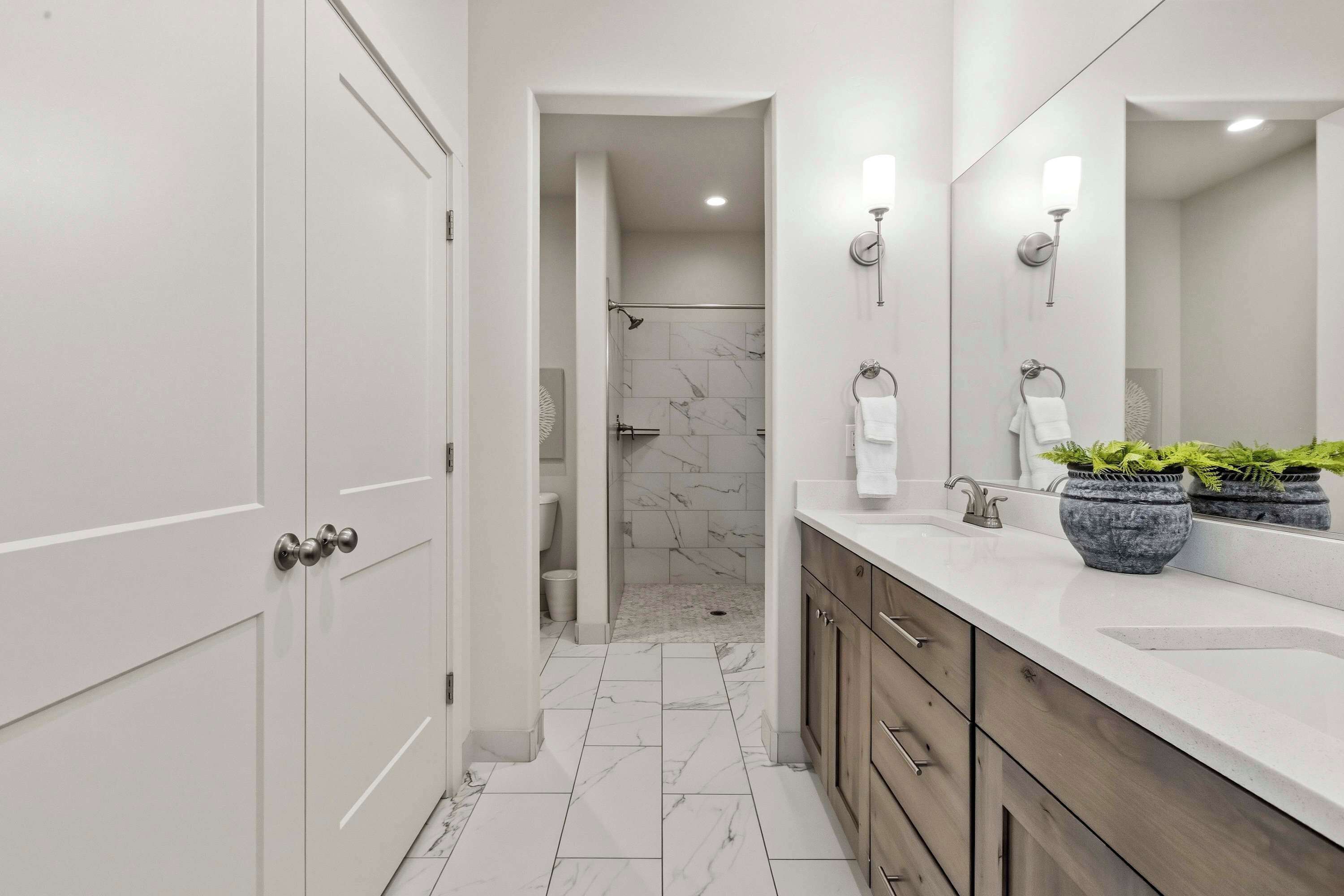 A modern bathroom with a shower, vanity, and marble flooring.