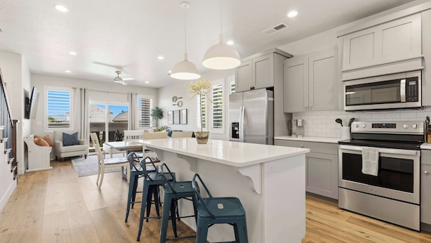 Een moderne keuken met een centraal eiland, roestvrijstalen apparatuur en een eethoek met barkrukken.
