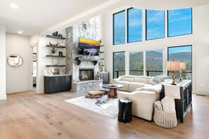 Un salón amplio con chimenea de piedra, ventanas grandes y un techo alto.